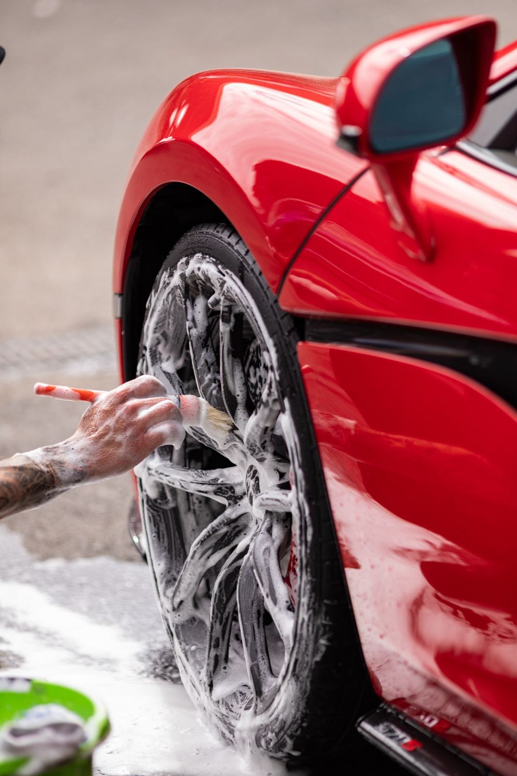 Brush detailing the front left alloy wheel of a McLaren 570S with Hexx Detailing Revolutions — behind-the-scenes business photography